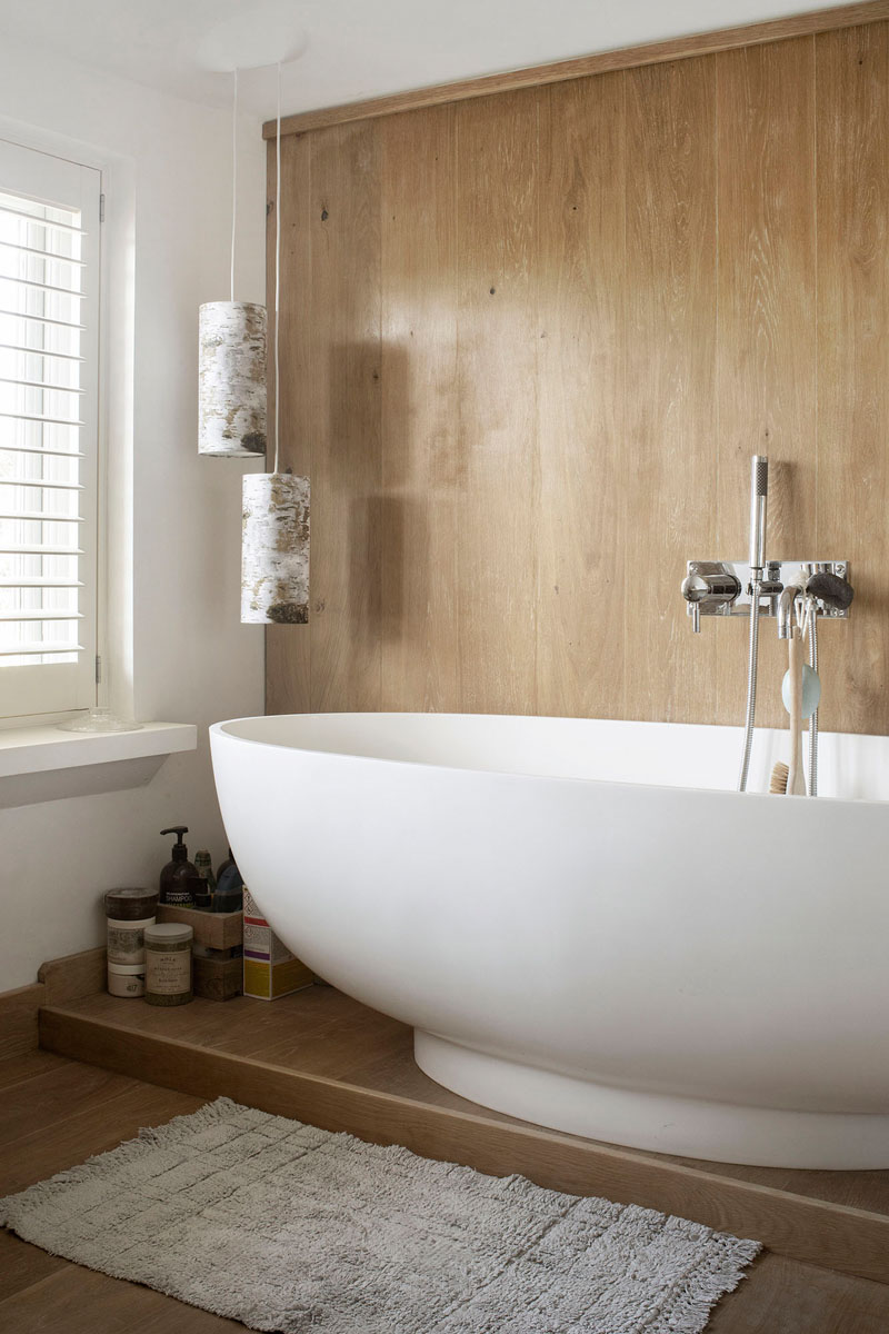 In this modern bathroom, a wood covered wall becomes the backdrop for the freestanding bathtub, while the window provides natural light. #ModernBathroom #WoodWall #BathroomDesignIdea