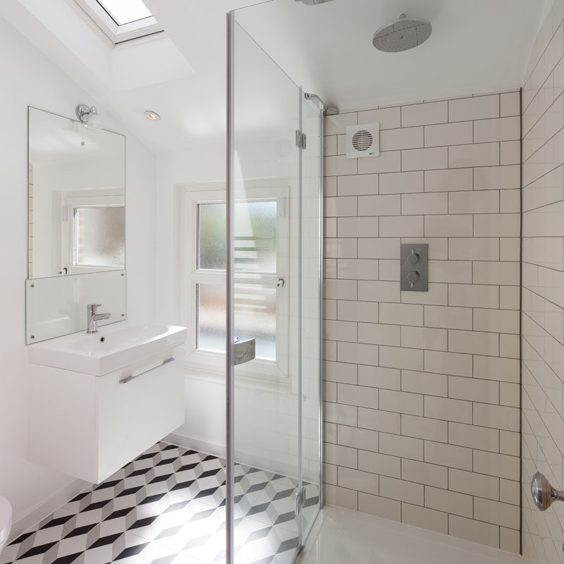 In this modern bathroom, a skylight adds natural light, while on the floor, a geometric tile pattern adds an artistic touch. #ModernBathroom #GraphicTiles #SubwayTiles