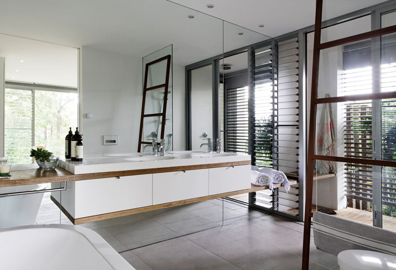 In this bathroom, a wall of mirrors helps to reflect the light from the windows, and also makes the room feel larger. #ModernBathroom #BathroomDesign #BathroomMirror