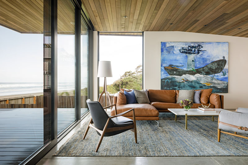 This beachfront living room has polished concrete flooring, a wood ceiling, and modern furnishings, that come together to create a comfortable space to relax. #LivingRoom #WoodCeiling #ConcreteFloor