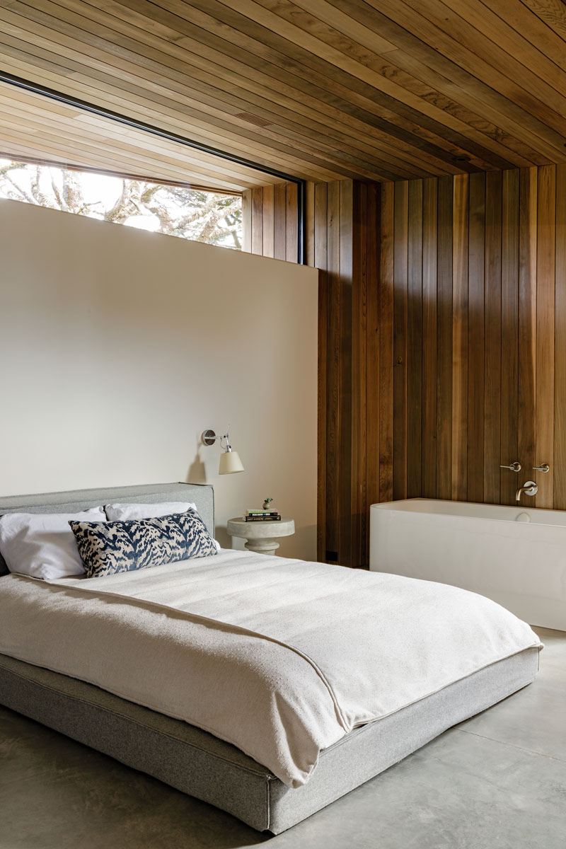 The cedar wood siding used on the exterior of this modern house, continues through to the interior, adding a natural touch and warmth to the bedroom. #WoodSiding #BedroomDesign #WoodWalls #ModernBedroom