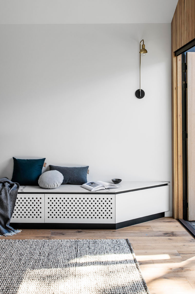 This modern house has lightly colored walls, a custom-built bench, and aged oak wood flooring. #ModernInterior #OakFlooring #WoodFlooring #CustomBench