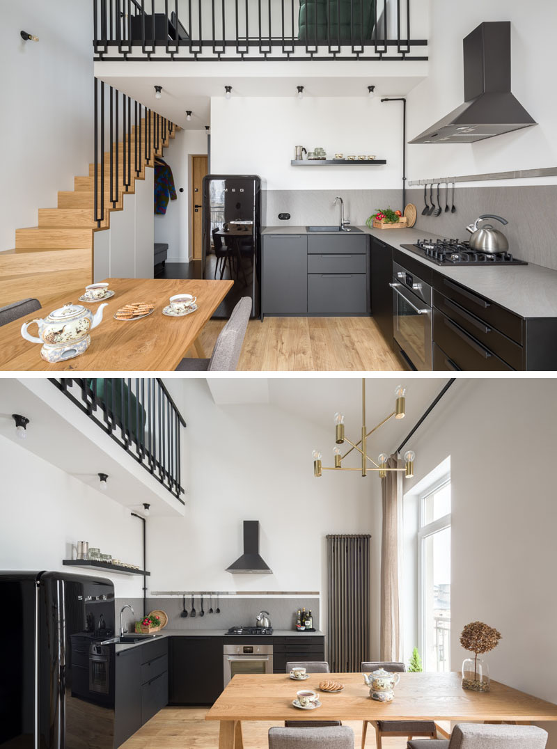 The entryway of this modern apartment opens up to the kitchen and dining area. In the kitchen, matte black cabinets have been combined with a grey countertop and a black fridge for a sleek and modern appearance. #BlackKitchen #ModernApartment #WoodStairs #ModernInterior