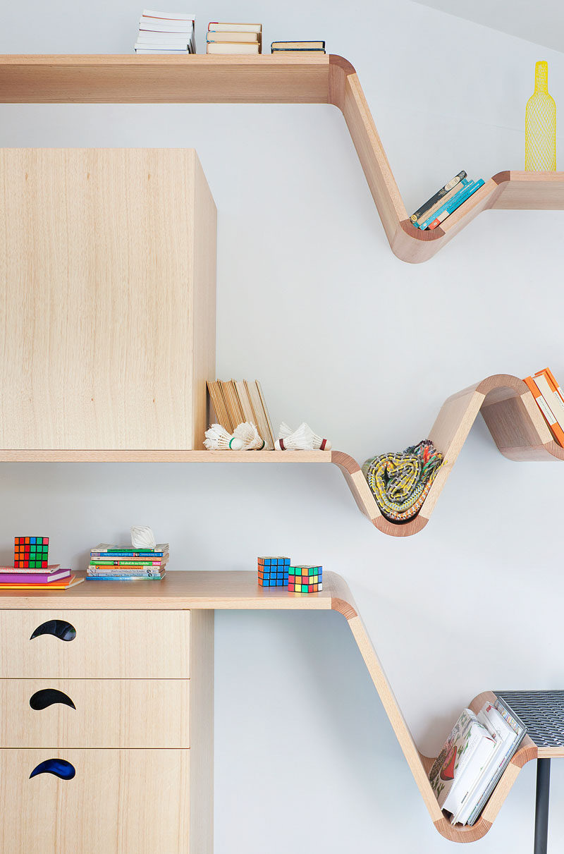 This modern kids bedroom features a custom designed wood desk that transition into benches and shelves. Floating shelving on the walls provides much need additional storage. #Shelving #KidsFurniture #FurnitureDesign