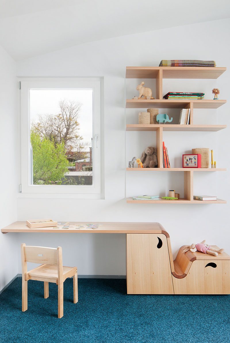 This modern kids bedroom features a custom designed wood desk that transition into benches and shelves. Floating shelving on the walls provides much need additional storage. #Shelving #KidsFurniture #FurnitureDesign