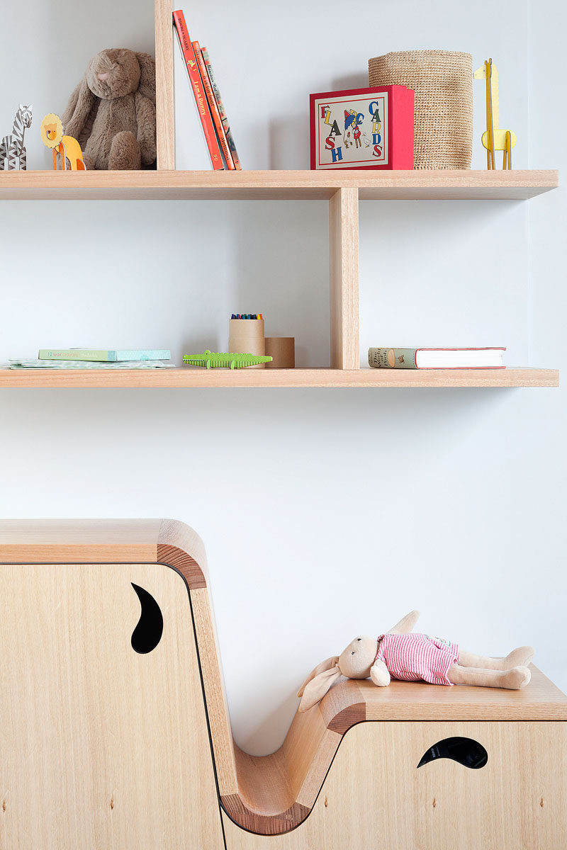 This modern kids bedroom features a custom designed wood desk that transition into benches and shelves. Floating shelving on the walls provides much need additional storage. #Shelving #KidsFurniture #FurnitureDesign