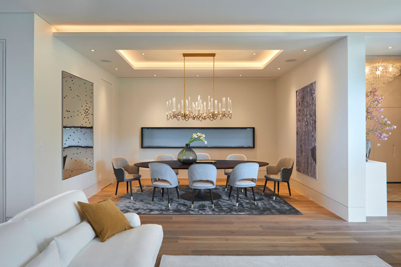 In this modern dining room, colorful art is highlighted on the walls, and a chandelier adds a delicate touch to the space. #ModernDiningRoom #DiningRoom