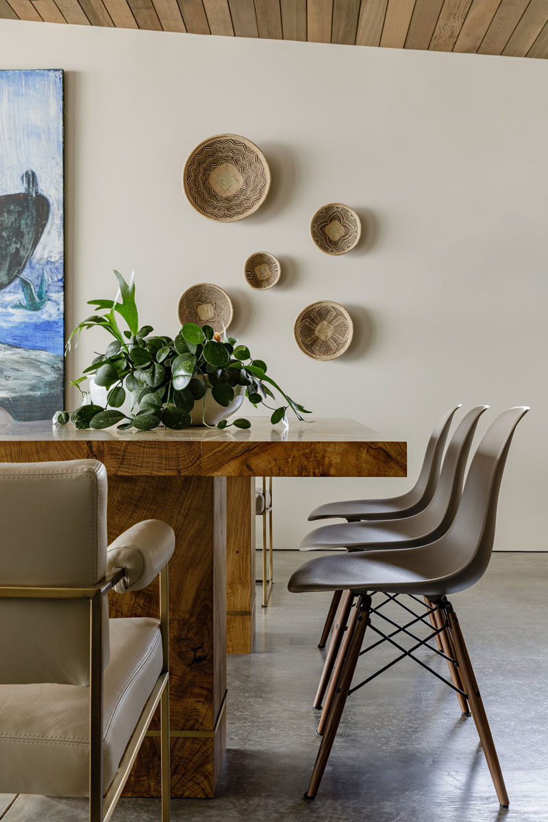 This modern dining room with a large wood table, features a display of mounted baskets on the wall. #DiningRoom #BasketDisplay