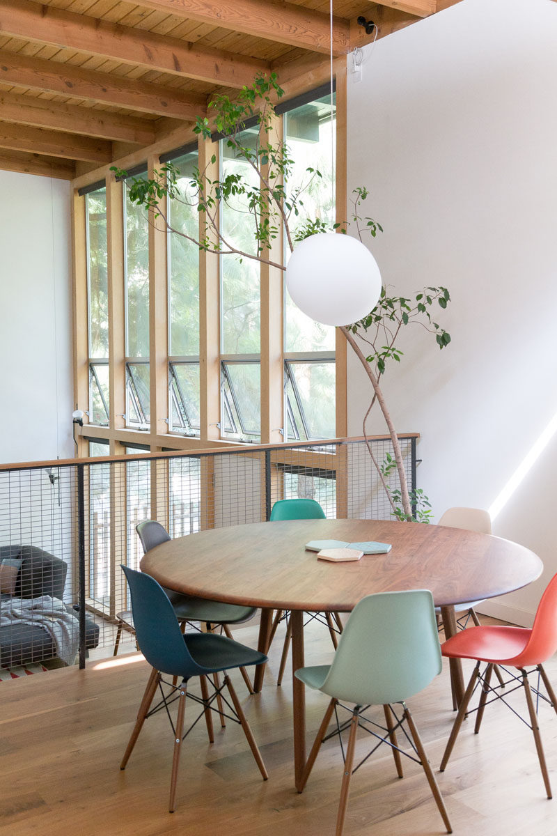 On the split level of this renovated mid century modern house, there's a open dining area with a view of the living room below. A single pendant light helps to define the location of the round dining table. #DiningRoom