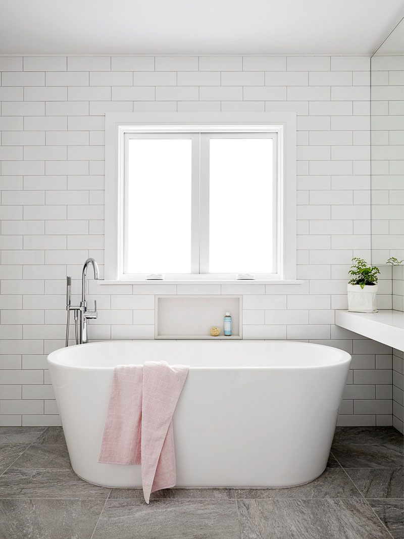 In this modern master bathroom, a freestanding bathtub sits below the window, while a small built-in shelf has been added to the subway tile wall. #ModernBathroom #FreestandingBathtub #BathroomIdeas