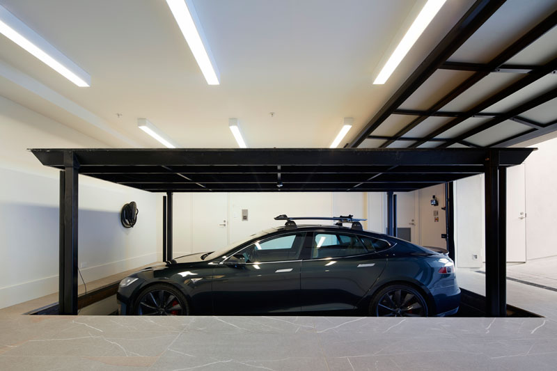 This multi-purpose garage boasts a pet spa, a Tesla Power Wall and parking for three cars, including a car vault that allows residents to easily lower a vehicle to the ground floor. #Garage #ModernGarage