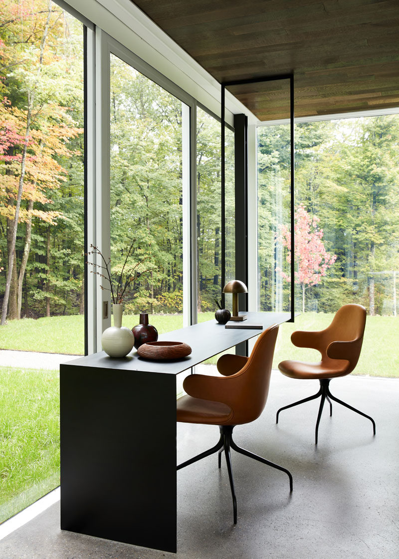 In this modern home office, the ceiling has been covered in wood, while the thin black desk hangs from the ceiling on one end, and meets the floor at the other end. #HomeOffice #Desk #InteriorDesign