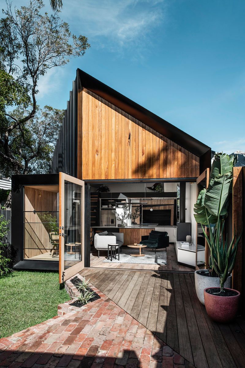 This modern house addition features a pitched roof, and is covered in a combination of standing seam metal siding, Silvertop Ash shiplap siding, and weatherboard. #ModernHouse #ModernAddition #BlackMetalSiding #WoodSiding