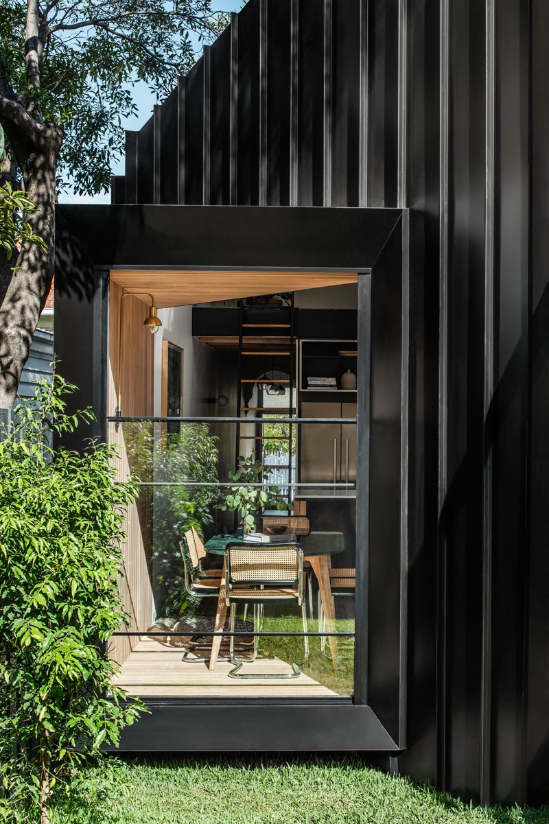 This modern house addition features a pitched roof, and is covered in a combination of standing seam black metal siding, Silvertop Ash shiplap siding, and weatherboard. #ModernHouse #ModernAddition #BlackMetalSiding #WoodSiding