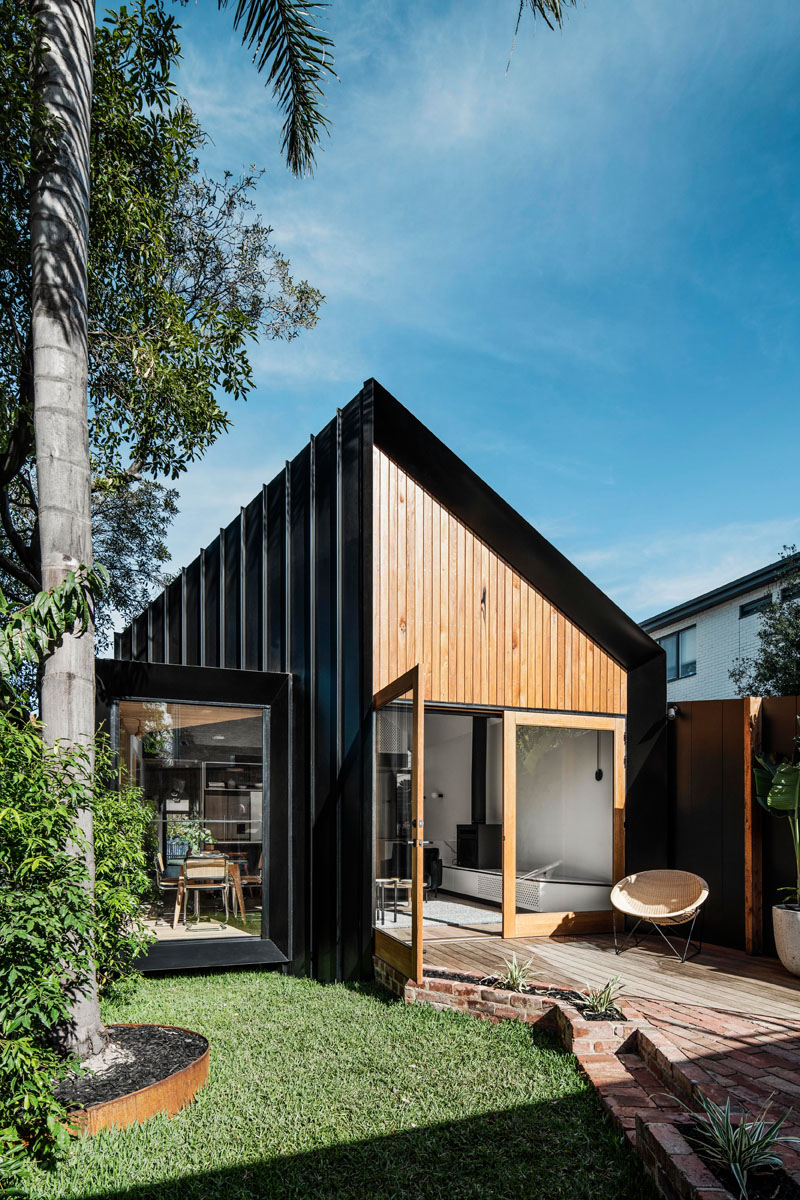 This modern house addition features a pitched roof, and is covered in a combination of standing seam black metal siding, Silvertop Ash shiplap siding, and weatherboard. #ModernHouse #ModernAddition #BlackMetalSiding #WoodSiding