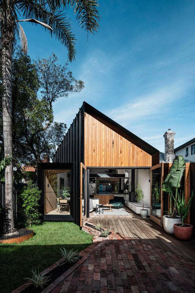 This modern house addition features a pitched roof, and is covered in a combination of standing seam black metal siding, Silvertop Ash shiplap siding, and weatherboard. #ModernHouse #ModernAddition #BlackMetalSiding #WoodSiding