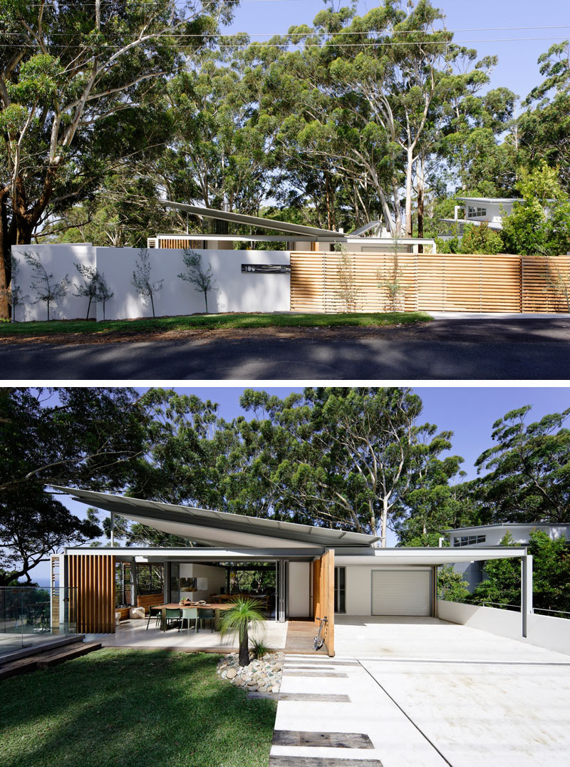 From the street, a wood fence opens to reveals this modern house with an angled roof and an expansive front yard with a covered outdoor dining room. #ModernHouse #HouseDesign #AngledRoof