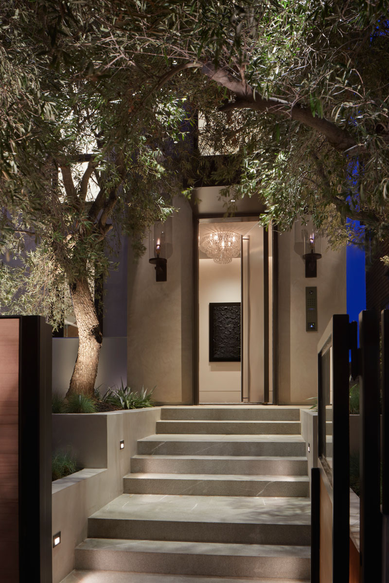 The tree and steps leading to this modern front door are highlighted at night by built-in lighting. #Landscaping #ExteriorStairs