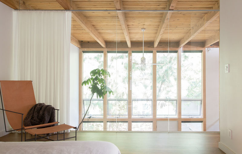 A framed wall closed off this master bedroom from the natural light, so the designers replaced the wall with a glass partition, and allowed the natural light from the living room windows to be enjoyed throughout the space. #GlassWall #Windows