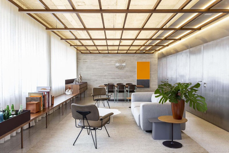 Throughout the main living space of this modern apartment, is a wood grid that has been suspended from the ceiling, that not only brings warmth to the interior, but also provides indirect lighting. #WoodGridCeiling #ModernApartment #HiddenLighting
