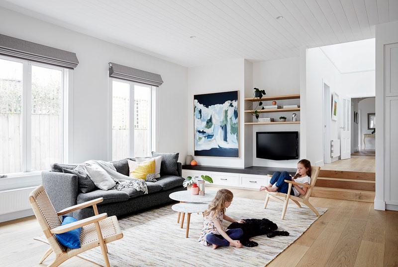 In this modern open plan living room, custom cabinetry lines the wall underneath the television, while abstract wall art and cushions add a touch of color. #LivingRoom #InteriorDesign #LivingRoomIdeas