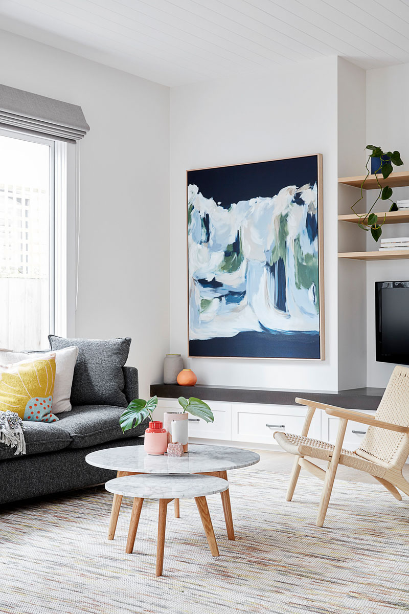 In this modern open plan living room, custom cabinetry lines the wall underneath the television, while abstract wall art and cushions add a touch of color. #LivingRoom #InteriorDesign #LivingRoomIdeas