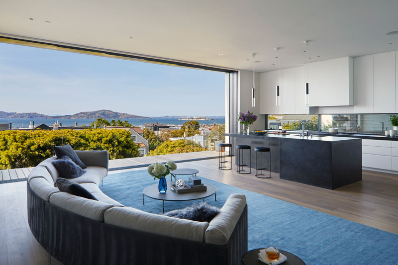 Sliding doors open the interior of this modern house to the balcony where uninterrupted water views can be enjoyed. #Balcony #Kitchen #LivingRoom