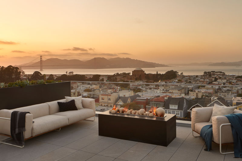 This modern house has a rooftop deck that features a lounge with a freestanding fire pit, and views of the city and Golden Gate Bridge. #RooftopDeck #OutdoorLounge