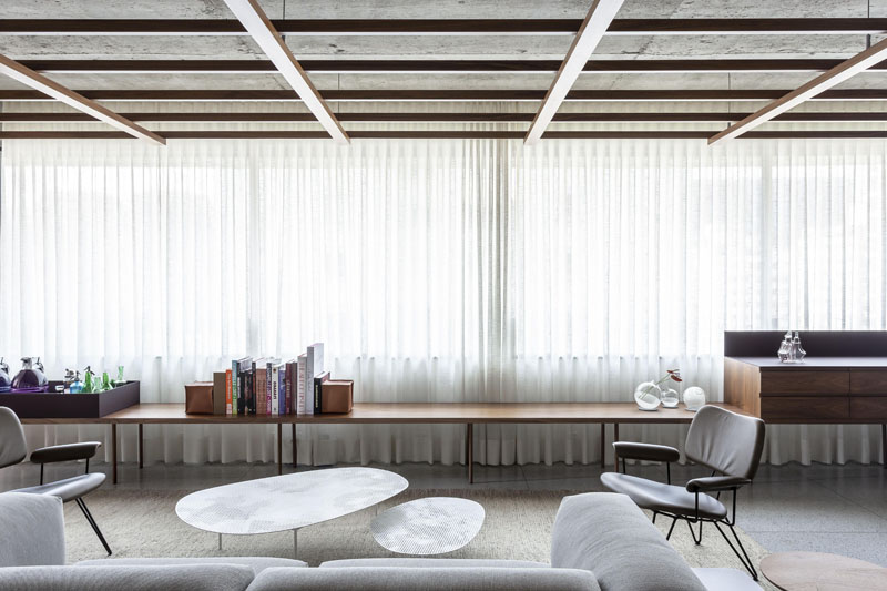 Throughout the main living space of this modern apartment, is a wood grid that has been suspended from the ceiling, that not only brings warmth to the interior, but also provides indirect lighting. #WoodGridCeiling #ModernApartment