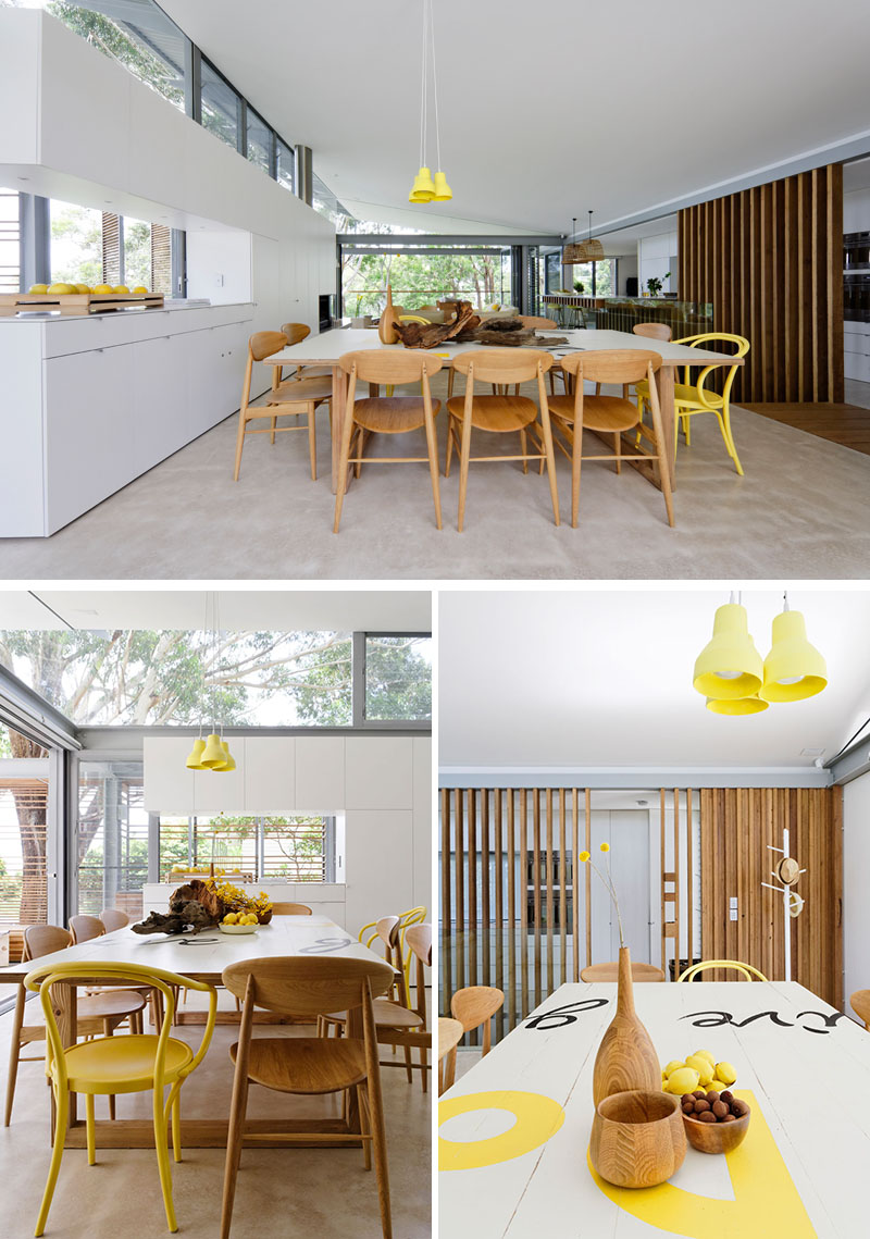 Yellow has been chosen as an accent color in this modern dining area to keep it light and bright. A wall of white cabinetry provides plenty of storage for the home, which is flexible enough to accommodate 14 people. #ModernDining #DiningTable #ModernInterior