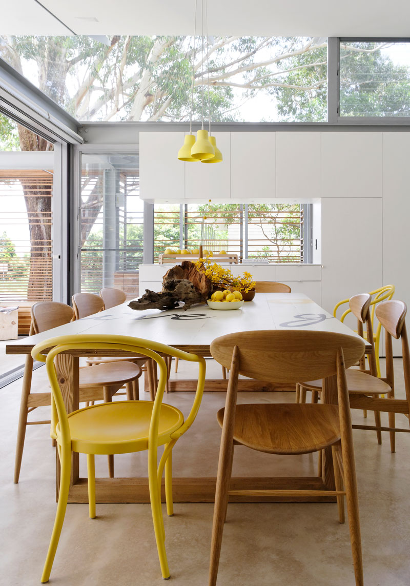 This modern dining area has pops of yellow to keep the interior bright with a sense of fun. #DiningRoom #YellowDecor #InteriorDesign #ModernDiningRoom