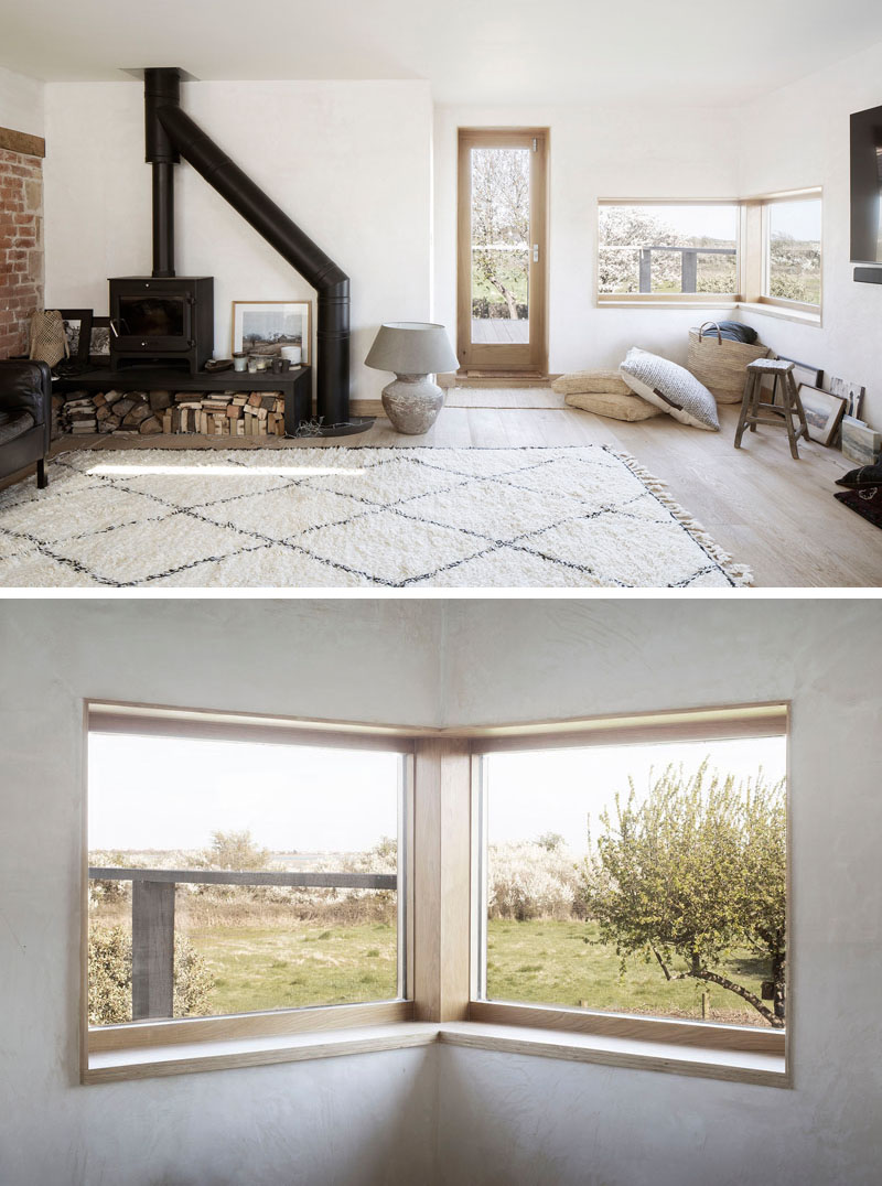 The main living space of this house addition features a wood-framed corner window, referencing an open book set into the wall at the height of a desk. #CornerWindow #LivingRoom