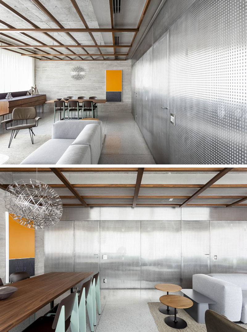 This modern apartment features a perforated stainless steel sheet panel wall that hides all of the apartment doors that lead to the kitchen, bedroom and bathroom. #StainlessSteelWall #ApartmentDesign #ApartmentInterior #HiddenDoors