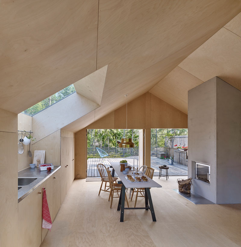 Windows filter the light through to the bright interior of this modern house that features birch plywood walls, ceiling, and floor. #PlywoodWalls #PlywoodInterior #Windows #Kitchen #Fireplace