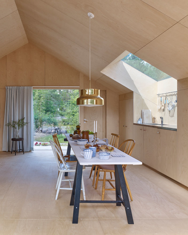 Windows filter the light through to the bright interior of this modern house that features birch plywood walls, ceiling, and floor. #PlywoodWalls #PlywoodInterior #Windows #Kitchen #Dining