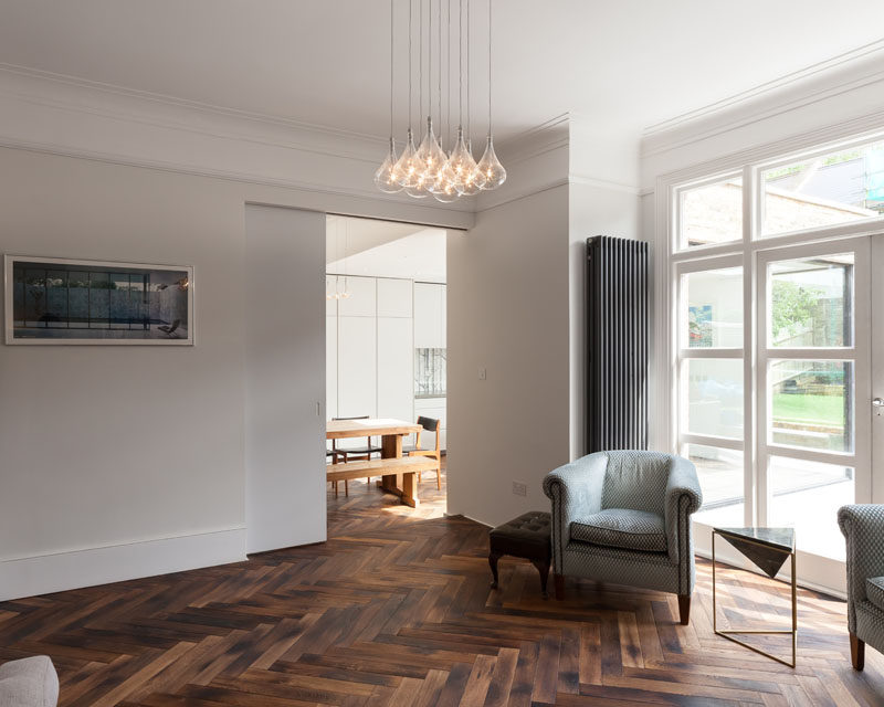 A large sliding door bridges the old and new areas of this home, while stained oak parquet flooring has been used throughout the ground floor. #ParquetFlooring #WoodFloors
