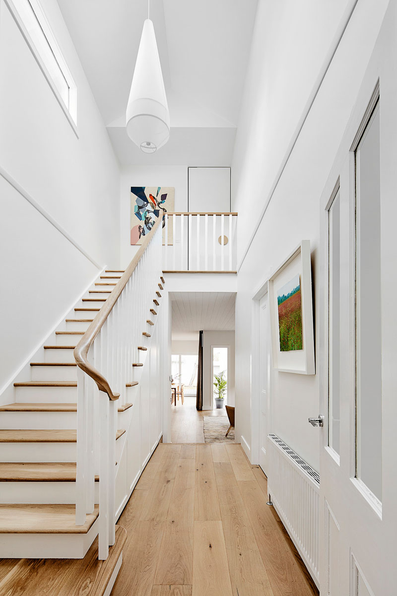 A central double height space containing the stair separates the new addition from the original home, and allows light to flow throughout the space. #Staircase #DoubleHeightEntryway