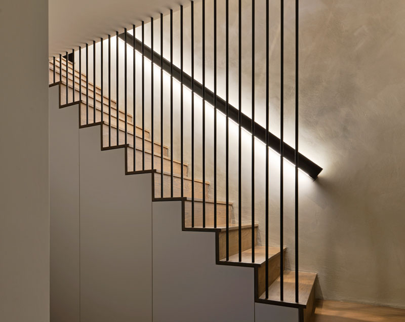 These modern wood stairs have a handrail with hidden lighting, and a floor-to-ceiling steel rod safety barrier. #WoodStairs #Handrail #BacklitHandrail