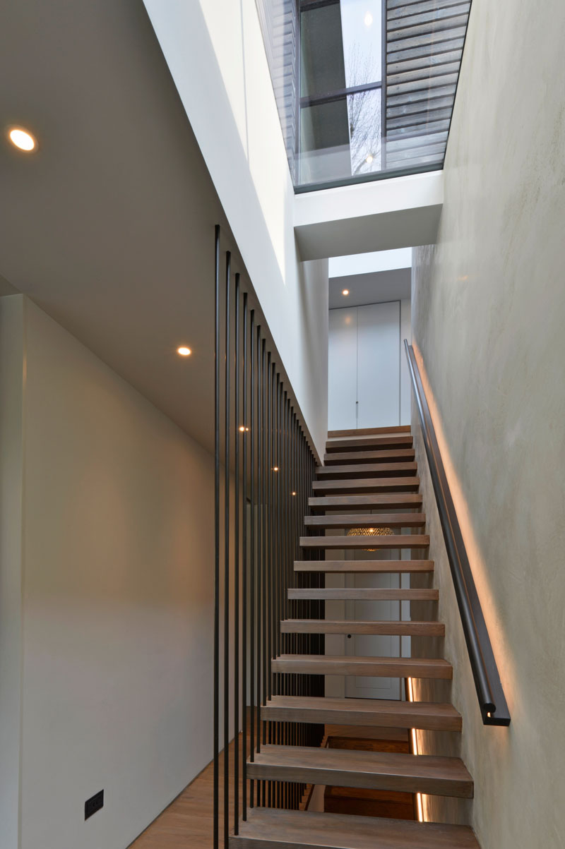 These modern wood stairs have a handrail with hidden lighting, and a floor-to-ceiling steel rod safety barrier. #WoodStairs #Handrail #BacklitHandrail
