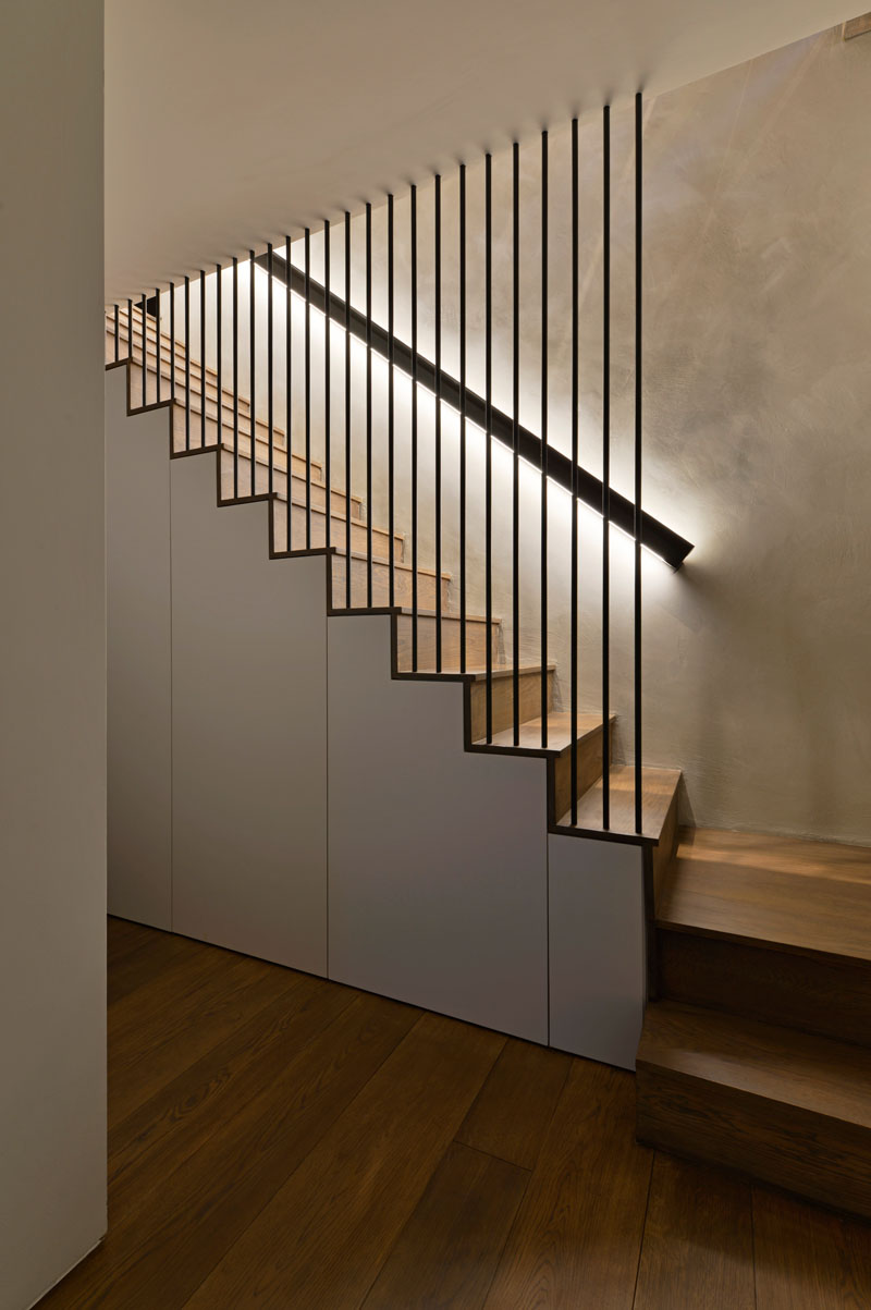 These modern wood stairs have a handrail with hidden lighting, and a floor-to-ceiling steel rod safety barrier. #WoodStairs #Handrail #BacklitHandrail