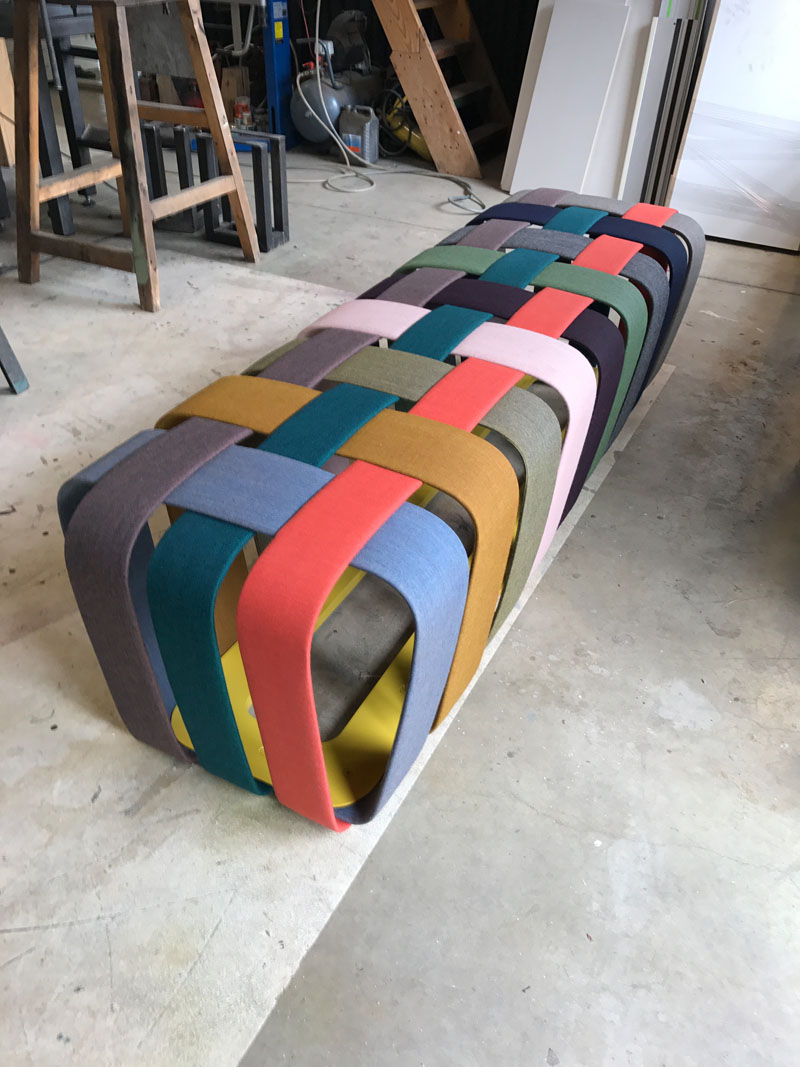 Max Lipsey has created the Woven Bench, that makes use of colorful upholstered strips of metal to create a modern bench. #ModernFurniture #ModernBench #ModernSeating