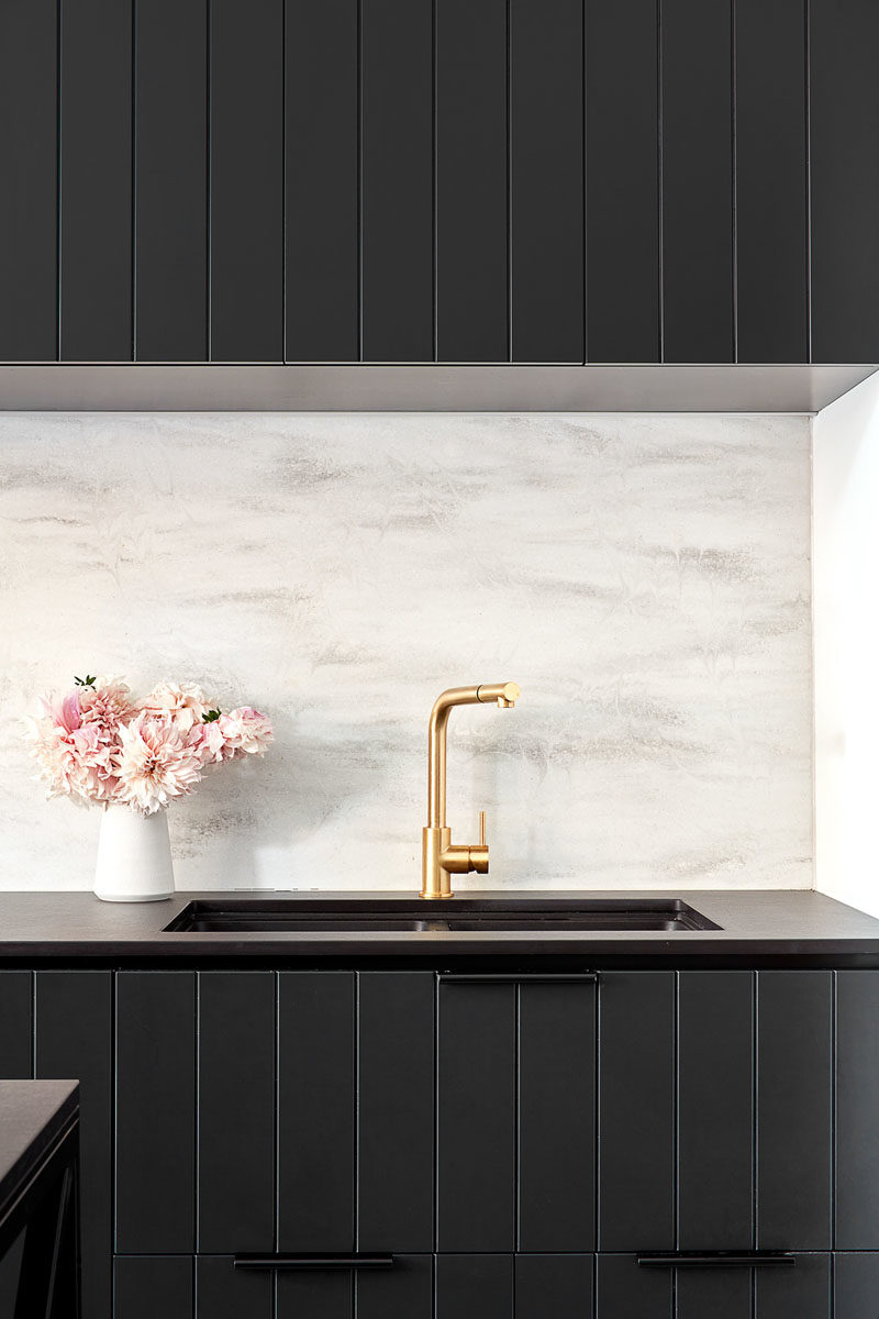 Kitchen Ideas - In this modern kitchen, black cabinets have been paired with a black countertop, gold fixtures, and a light grey backsplash. #BlackKitchen #KitchenIdeas #BlackCabinets