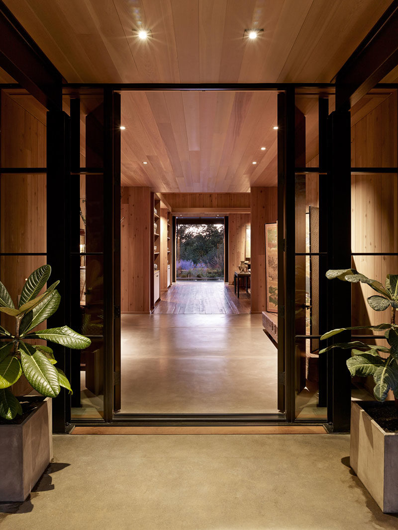 Black-framed windows and a wood front door welcome visitors to this modern farmhouse. #Entryway #FrontDoor