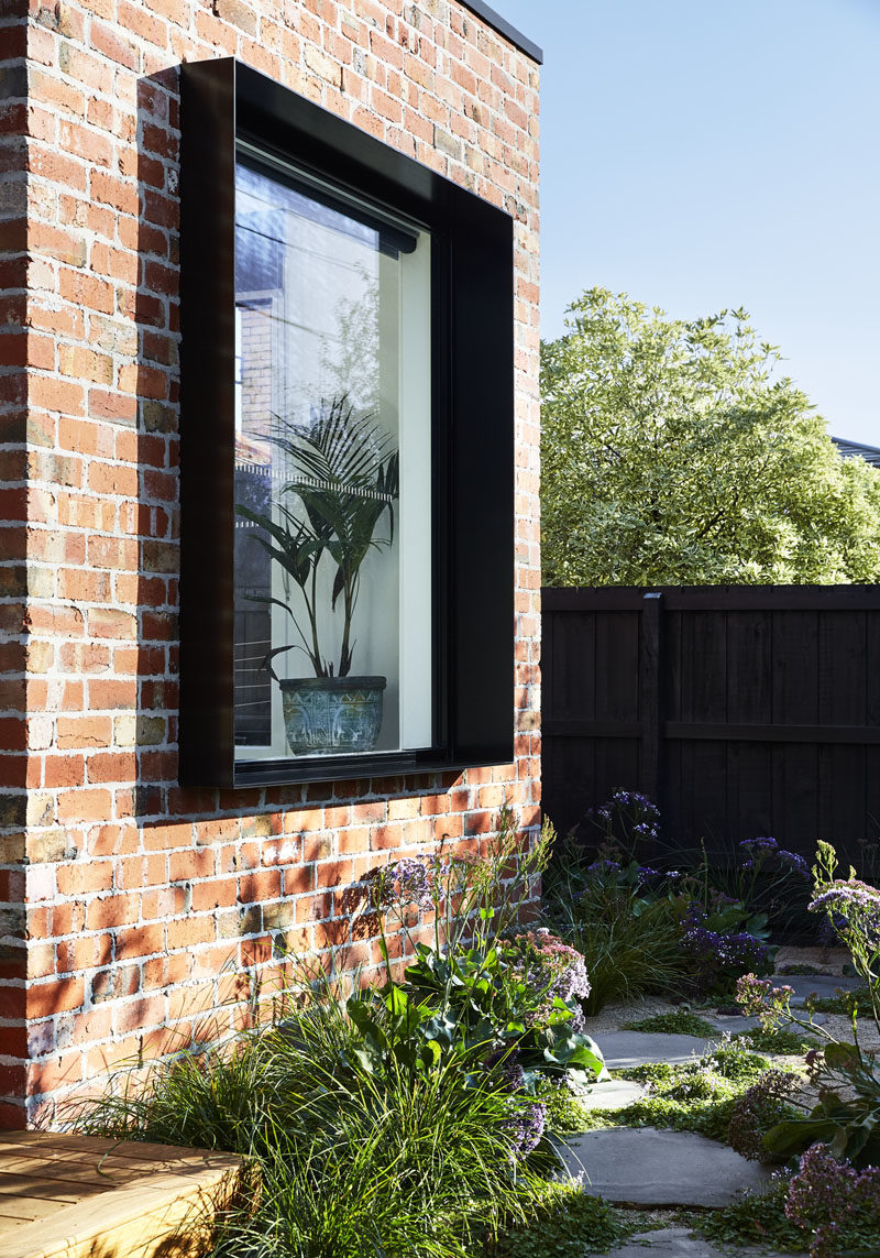 A protruding black frame highlights this window on a modern house that also features recycled brick. #BlackWindowFrame #RecycledBrick #ModernHouse