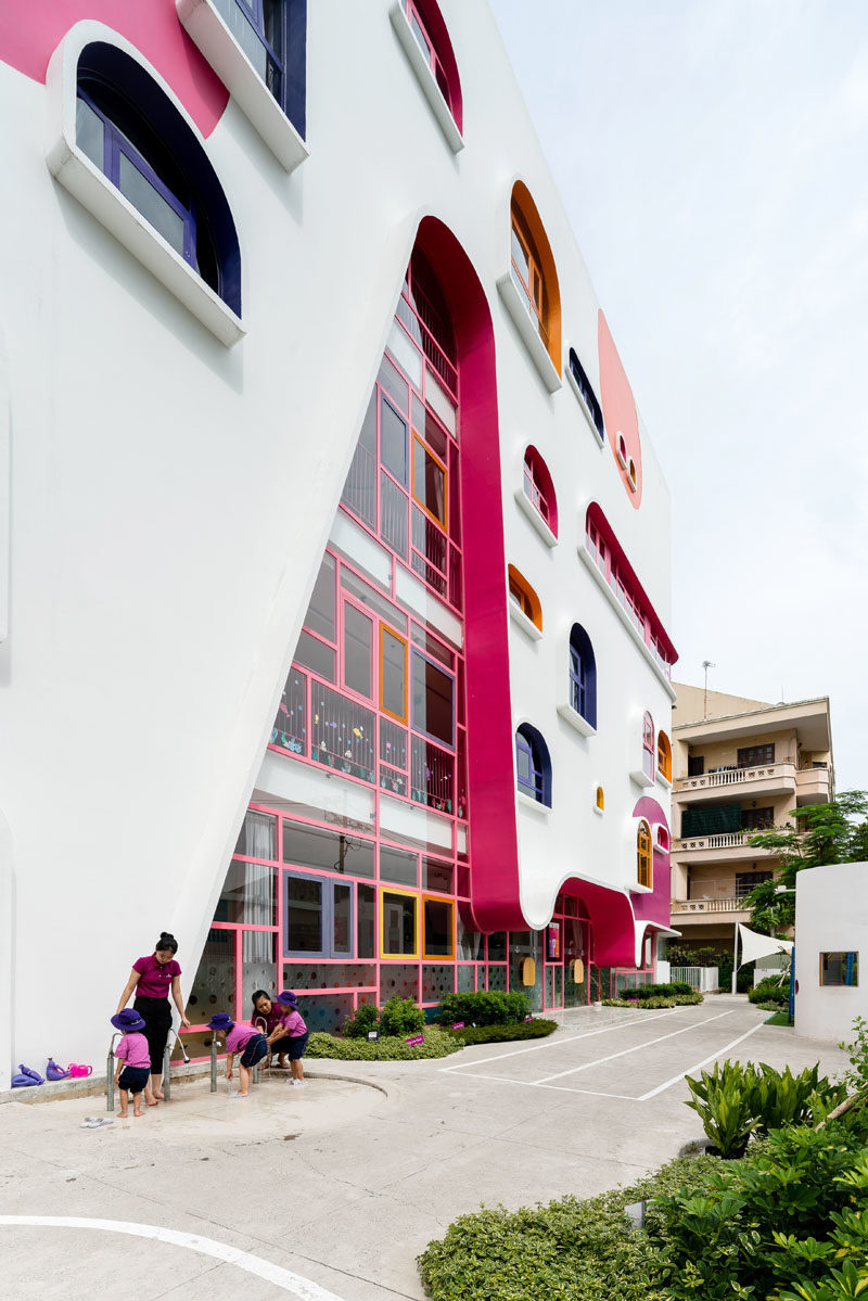 Facade Ideas - The white facade of the kindergarten features pops of color that complement the colorful geometrically shaped window frames. #FacadeIdeas #Architecture #UniqueWindowShapes