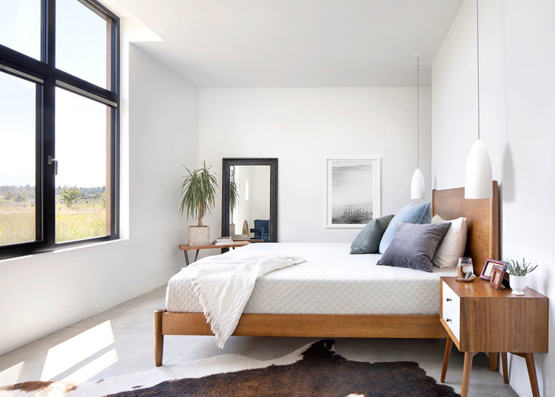 Bedroom Ideas - In this modern bedroom, wood furnishings and a plan help to bring nature indoors, while the black framed windows allow an abundance of natural light to fill the room. #BedroomIdeas #BedroomDesign #ModernBedroom