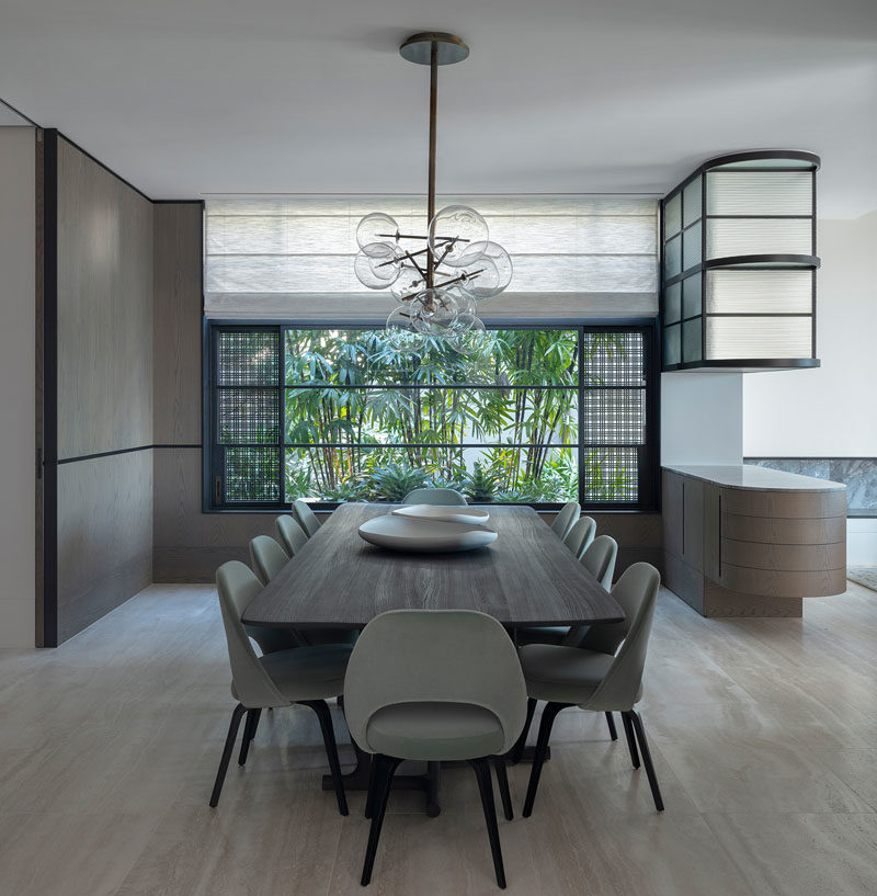 Dining Room Ideas - In this contemporary dining room, walnut wall paneling adds warmth to the room, that also features travertine flooring. To the right of the dining table is a bar where the owner keeps his collection of rare whiskeys. #DiningRoom #TravertineFlooring #WalnutPanels