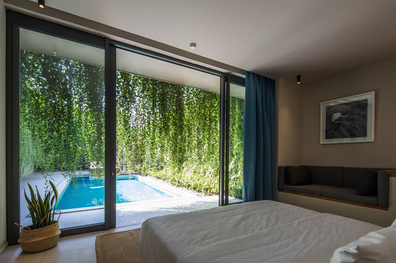 Bedroom Ideas - In this modern bedroom design, a built-in couch has been added along one wall, while hanging plants provide privacy. #HangingPlants #BuiltInCouch #BedroomDesign #BedroomIdeas