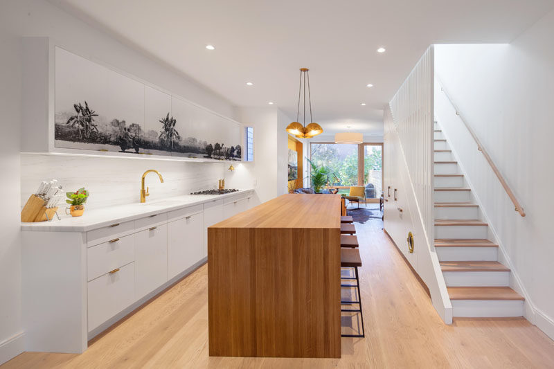 Kitchen Ideas - A black and grey mural has been added to the upper cabinets in this white and wood modern kitchen, creating a central focal point for the open plan interior.  #KitchenIdeas #KitchenCabinets #Mural #Art #KitchenDesign #ModernKitchen