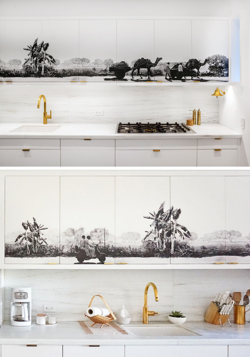 Ý tưởng nhà bếp - Một bức tranh tường màu đen và xám đã được thêm vào các tủ trên trong nhà bếp hiện đại màu trắng và gỗ này, tạo ra điểm nhấn trung tâm cho nội thất không gian mở.  # BếpIdeas # BếpNhà bếp # Tranh tường # Nghệ thuật # Nhà bếpThiết kế # Hiện đạiNhà bếp